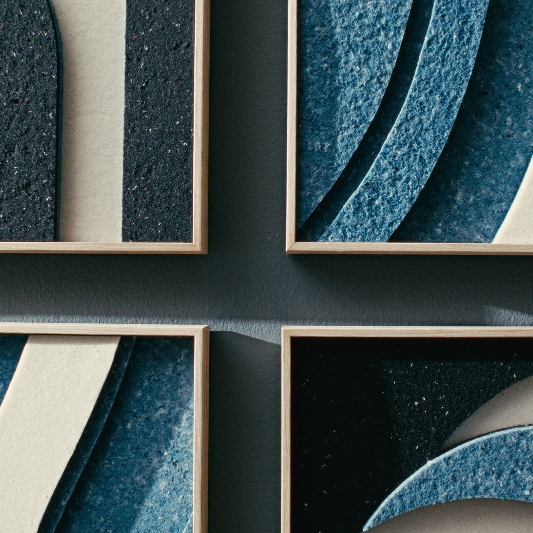 Close-up of decorative acoustic tiles by Arturel, showcasing layered blue and black textures in wooden frames for sound absorption.